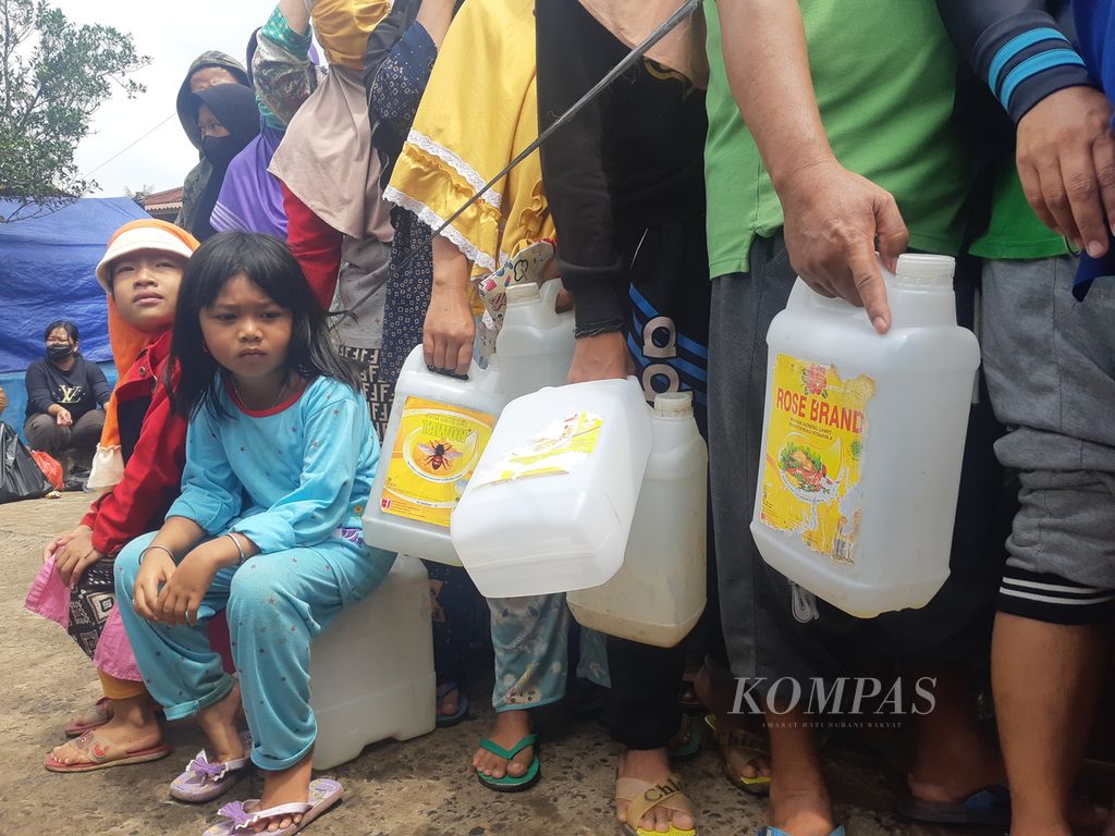 Dua anak kecil sedang duduk di atas jeriken minyak sembari menunggu antrean operasi pasar di Pasar Alang-Alang Lebar, Palembang, Sumatera Selatan, Sabtu (5/3/2022). Sampai saat ini distribusi minyak goreng masih bermasalah menyebabkan warga kesulitan mendapatkan minyak goreng.