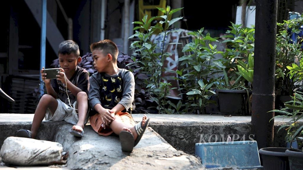 Anak-anak bermain dengan gawai di kawasan Cideng, Jakarta Pusat, Rabu (18/7/2018). Penggunaan gawai oleh anak-anak memerlukan pengawasan, panduan, dan pembatasan dari orangtua.