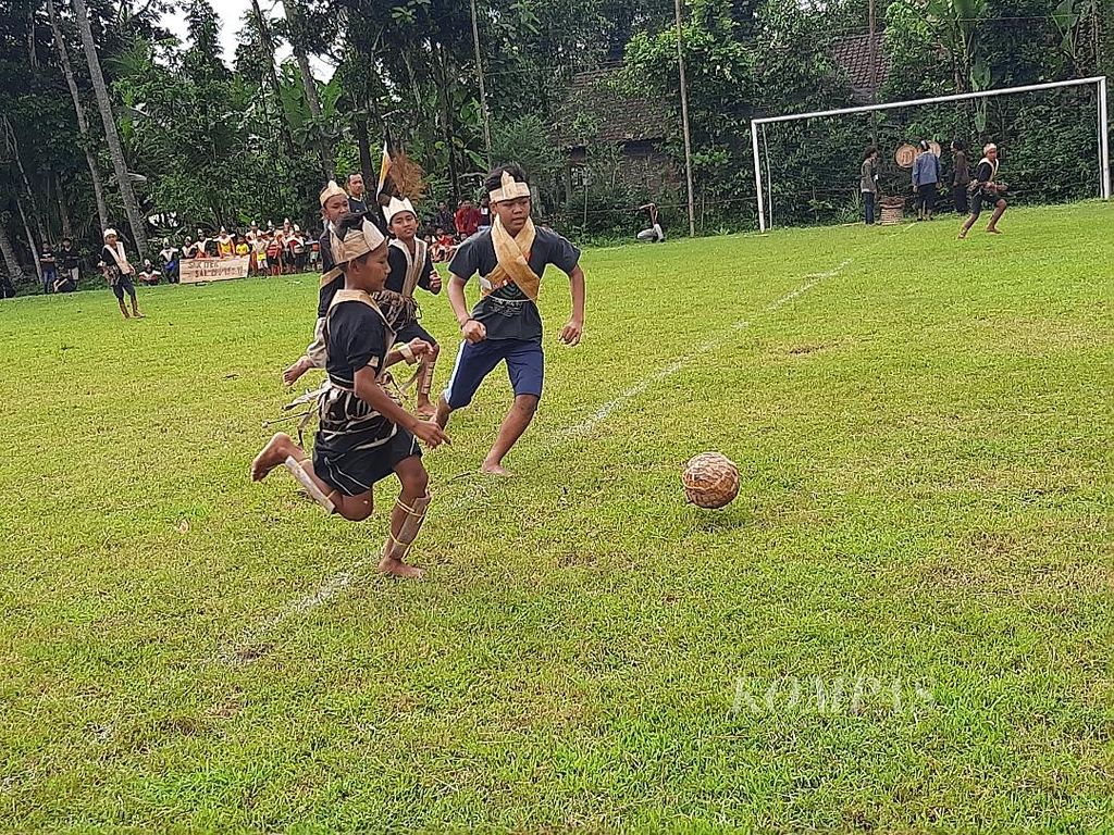 Sejumlah anak asyik bermain sepak bola dengan mengenakan baju berhiaskan pelepah dan daun pisang serta menendang bola yang terbuat dari gulungan pelepah pisang, Sabtu (21/5/2022).