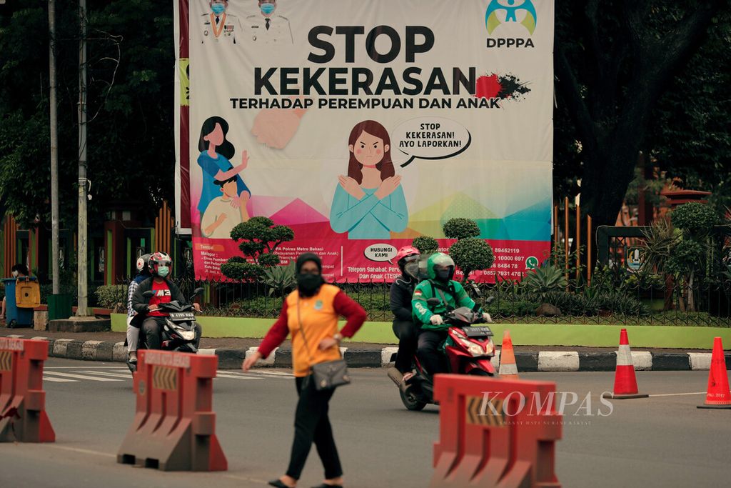 Warga melintasi baliho ajakan untuk menghentikan kekerasan terhadap perempuan dan anak di pintu masuk Kantor Walikota Bekasi, Jawa Barat, Rabu (23/6/2021). 