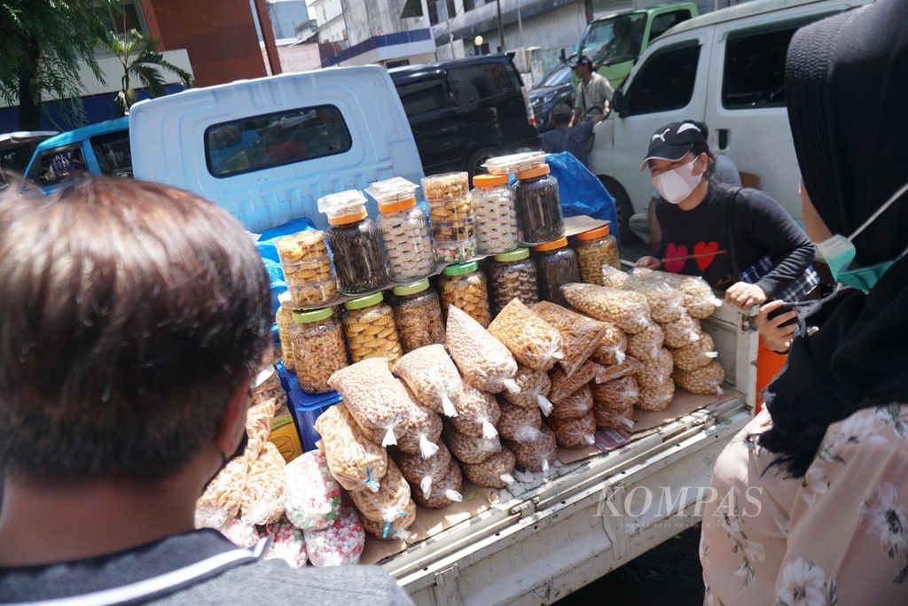Seorang pedagang membuka terpal untuk memperlihatkan kue-kue kering atau kukis yang ia jual di daerah Wenang dekat Pelabuhan Manado, Sulawesi Utara, Senin (19/12/2022). Inspeksi satuan polisi pamong praja memaksa para pedagang untuk berdagang secara sembunyi-sembunyi.