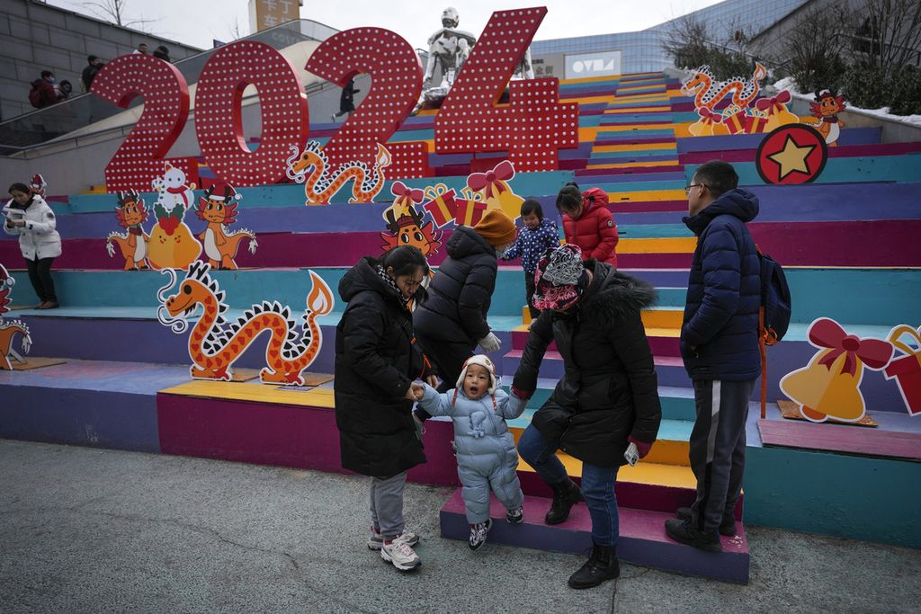  Keluarga di China sedang berjalan-jalan di pusat perbelanjaan yang memajang dekorasi naga di Beijing, China, 1 Januari 2024.