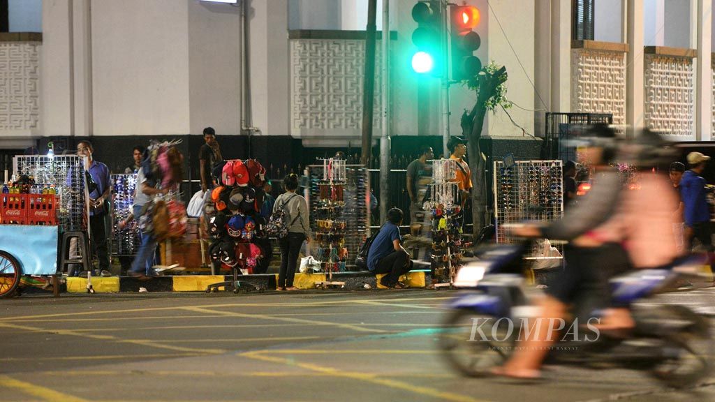 Pedagang berkumpul dan menjajakan dagangan di perempatan depan Museum Bank Mandiri, Jakarta Barat, Minggu (5/11) malam. Mereka berkumpul sambil menunggu kepergian petugas satuan polisi pamong praja (satpol PP) yang menertibkan kawasan di sekitar Taman Fatahillah dari para pedagang.