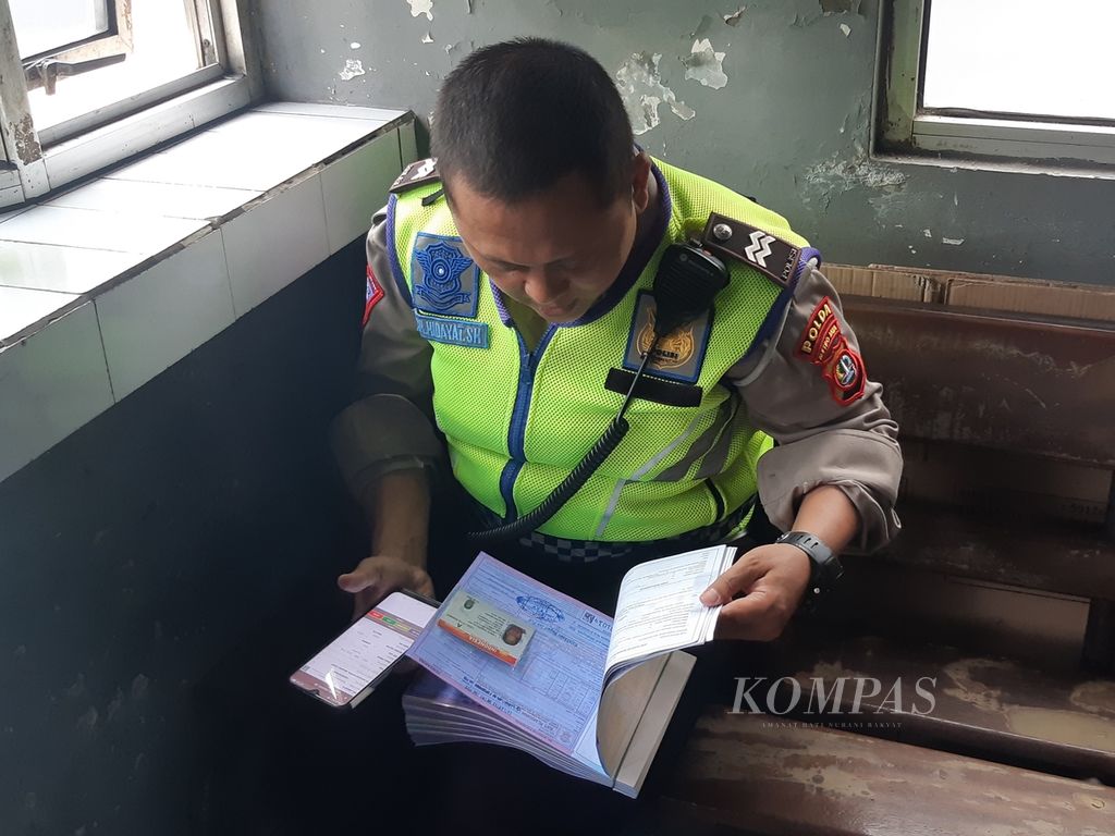 Seorang polisi memeriksa surat tilang pelanggar aturan ganjil genap di pos polisi, di Jalan Salemba Raya, Jakarta Pusat, 13 Juni 2022. Data pelanggar di surat itu diunggah ke platform tilang elektronik. 