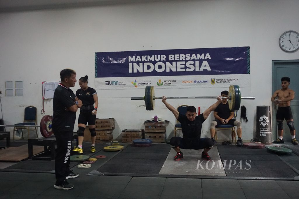 Atlet angkat besi Indonesia, Ricko Saputra, berlatih di bawah bimbingan pelatihnya, Dirdja Wihardja, di pemusatan latihan angkat besi, Mess Kwini, Jakarta, Rabu (29/11/2023).