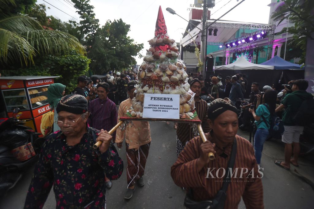 Warga mengusung kue apem yang dibentuk gunungan saat mengikuti kirab ruwahan dalam Sarkemfest atau Festival Sarkem 2024 di Jalan Sosrowijayan, Yogyakarta, Jumat (1/3/2024).