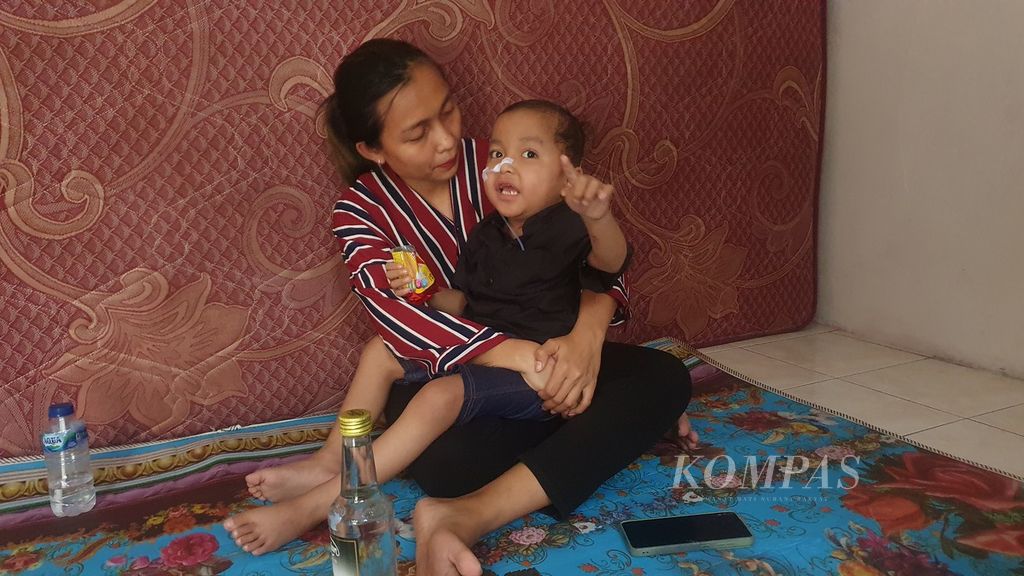 Septiana Juwita Sari (29) memangku anaknya, Alvaro (4), yang masih berjuang untuk sembuh setelah mengalami gangguan ginjal akut progresif atipikal atau GGAPA saat ditemui di rumah kontrakannya di Jalan Masjid, Lenteng Agung, Jagakarsa, Jakarta Selatan, Minggu (9/7/2023).