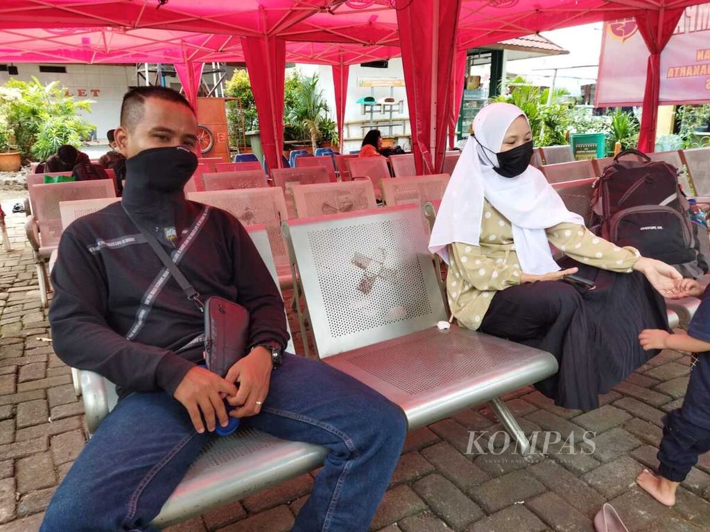 Alam (29) beserta istri dan anaknya menunggu kedatangan bus tujuan Palembang di ruang tunggu di Terminal Kalideres, Jakarta Barat, Senin (11/4/2022).