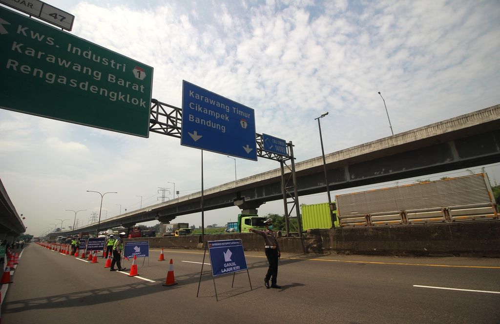 Personel Polres Karawang mengatur lalu lintas saat uji coba pembatasan pelat nomor kendaraan ganjil genap di Km 47 Tol Jakarta-Cikampek, Selasa (26/4/2022). 