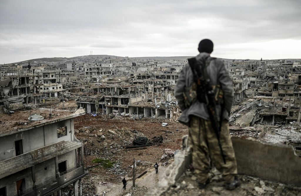 Foto dokumentasi tanggal 30 Januari 2015 ini memperlihatkan seorang anggota militer Kurdi berdiri di atap sebuah gedung sambil mengamati Desa Halimee, sebelah timur kota Kobane atau yang juga dikenal dengan kota Ain al-Arab, Suriah. 
