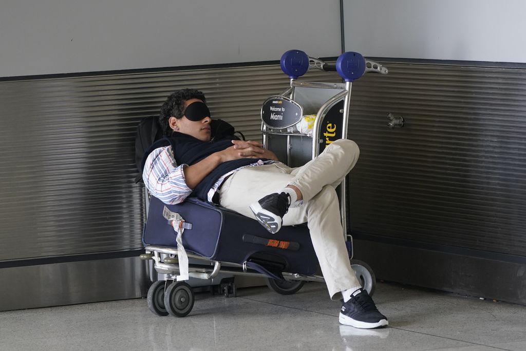 Seorang calon penumpang pesawat tidur siang saat menunggu penerbangan pesawatnya di Bandara Internasional Miami, AS, pada 1 Juli 2022. 