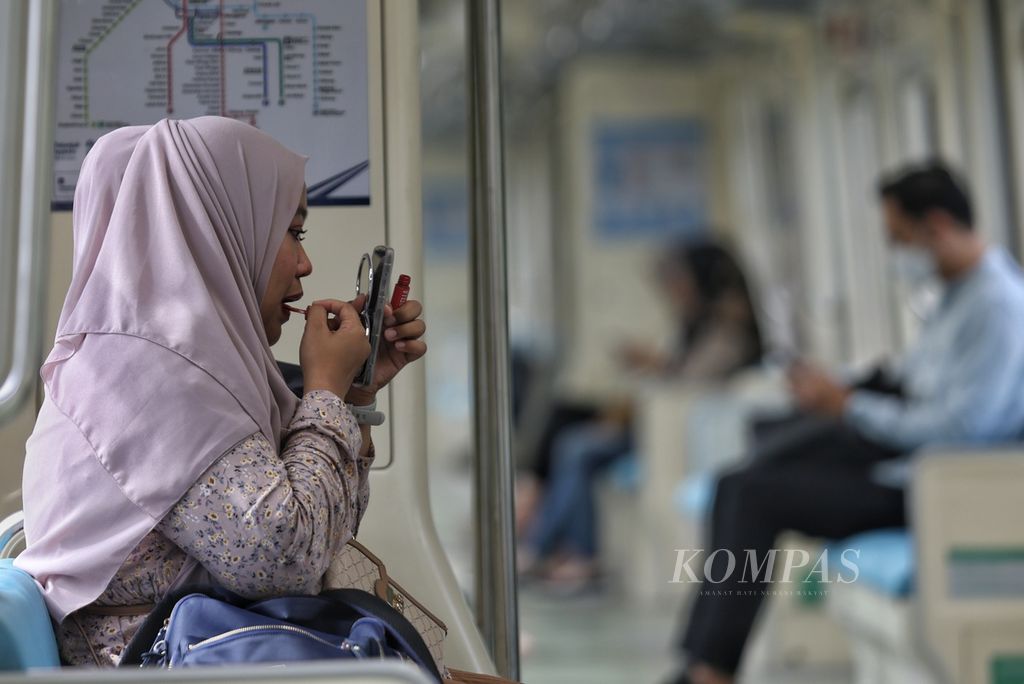 Seorang pengguna LRT merias diri di dalam kereta di Stasiun LRT Dukuh Atas, Jakarta, Jumat (1/3/2024). 