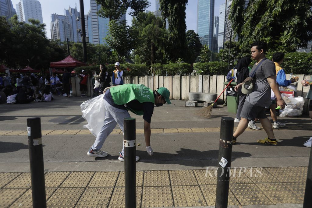 Sukarelawan Jakarta Osoji Club (JOC) memungut sampah di kawasan Plaza Tenggara kompleks Gelora Bung Karno (GBK), Jakarta Selatan, Minggu (30/6/2024). 