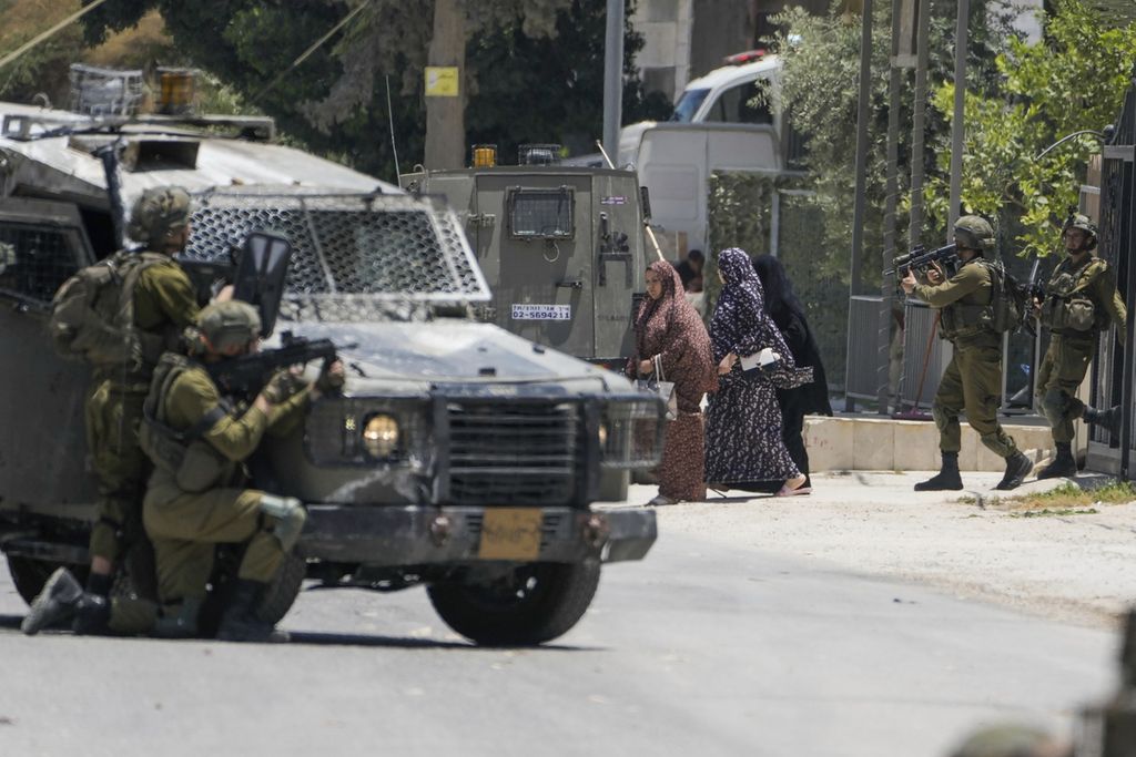 Militer Israel mengawal beberapa perempuan kerabat seorang warga Palestina yang tengah diburu di Urif, Tepi Barat, Kamis (29/6/2023). Militer Israel mengejar warga Palestina yang diduga terlibat dalam kekerasan yang mengakibatkan warga Yahudi tewas.  