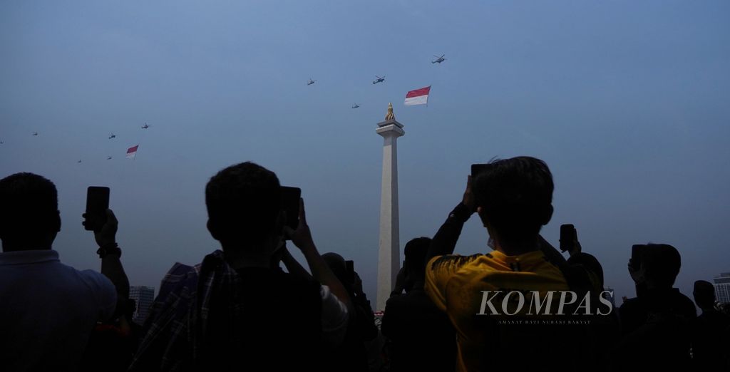 Warga dengan antusias menyambut defile helikopter TNI dan Polri yang melintas di kawasan Monumen Nasional, Jakarta, dengan membawa bendera Merah Putih raksasa untuk memeriahkan peringatan Hari Ulang Tahun Ke-78 RI di Istana Merdeka, Jakarta, Kamis (17/8/2023). 