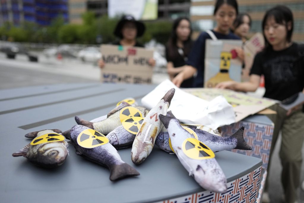 Ikan mainan yang ditempel stiker penanda radioaktif dibawa pengunjuk rasa Korea Selatan pada Agustus 2023 di Seoul. Mereka memprotes keputusan Jepang membuang air limbah PLTN Fukushima. 