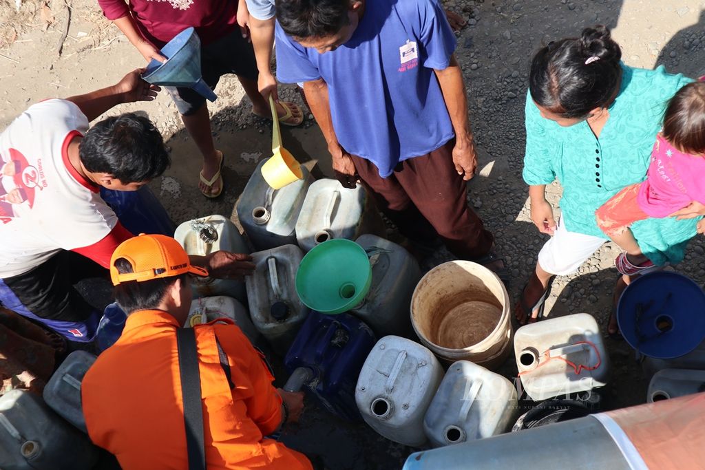 Warga di Desa Slangit, Kecamatan Klangenan, Kabupaten Cirebon, Jawa Barat, mengangkut bantuan air bersih dari BPBD Kabupaten Cirebon dan PDAM Tirta Jati, Juli 2019.