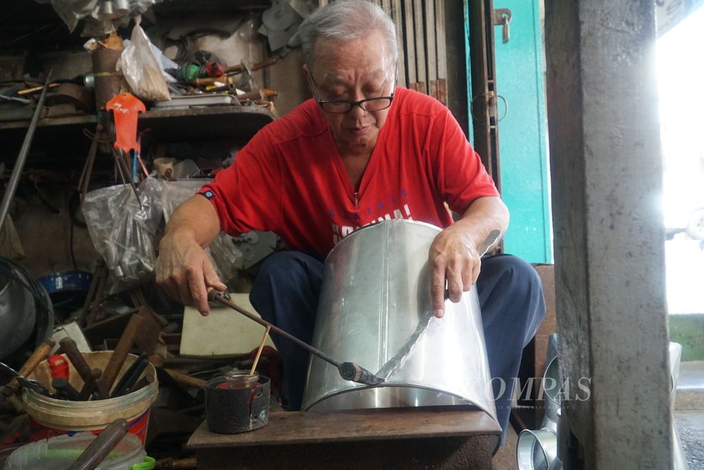 Seorang tukang timah sedang mematri untuk membuat tong susu kedelai di toko Ho Nyen Foh di Jalan Bishopgate, kawasan Kuching Old Bazaar, kota Kuching, Sarawak, Malaysia, Kamis (22/2/2024). 