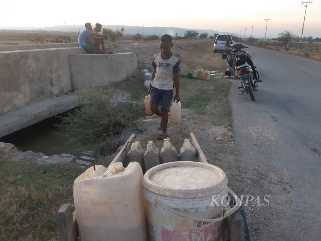 Seorang anak selesai mengambil air keruh di parit dekat persawahan Desa Bena, Kecamatan Amanuban Selatan, Kabupaten Timor Tengah Selatan, Nusa Tenggara Timur, Selasa (21/11/2023).  Air itu merupakan genangan hujan. Selama musim kemarau, hujan baru terjadi beberapa hari sebelumnya.