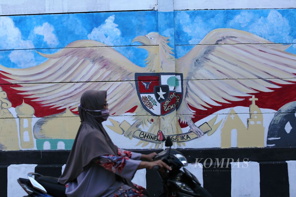  A female driver crosses the mural "Indonesian Diversity" in Pancasila Village, Harapan Jaya Village, North Bekasi District, Bekasi City, West Java, Friday (13/5/2022).