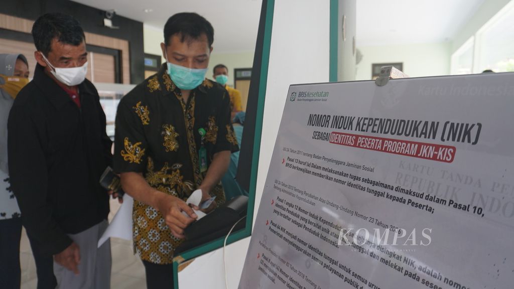 Sujadi (60) dibantu oleh petugas puskesmas memasukkan data kepesertaan JKN-KIS untuk didaftarkan dalam sistem pelayanan kesehatan di Puskesmas Temon 1 Kulon Progo, Yogyakarta, Jumat (4/2/2022). Jumlah peserta program JKN-KIS yang tercatat saat ini sebanyak 223 juta orang.