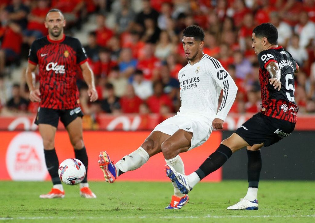 Gelandang Real Madrid, Jude Bellingham (tengah), mengontrol bola saat bertanding melawan RCD Mallorca pada laga Liga Spanyol di Palma de Mallorca, Minggu (18/8/2024). Bellingham tak bisa bermain saat laga lawan Real Valladolid, Minggu (25/8/2024), karena cedera.