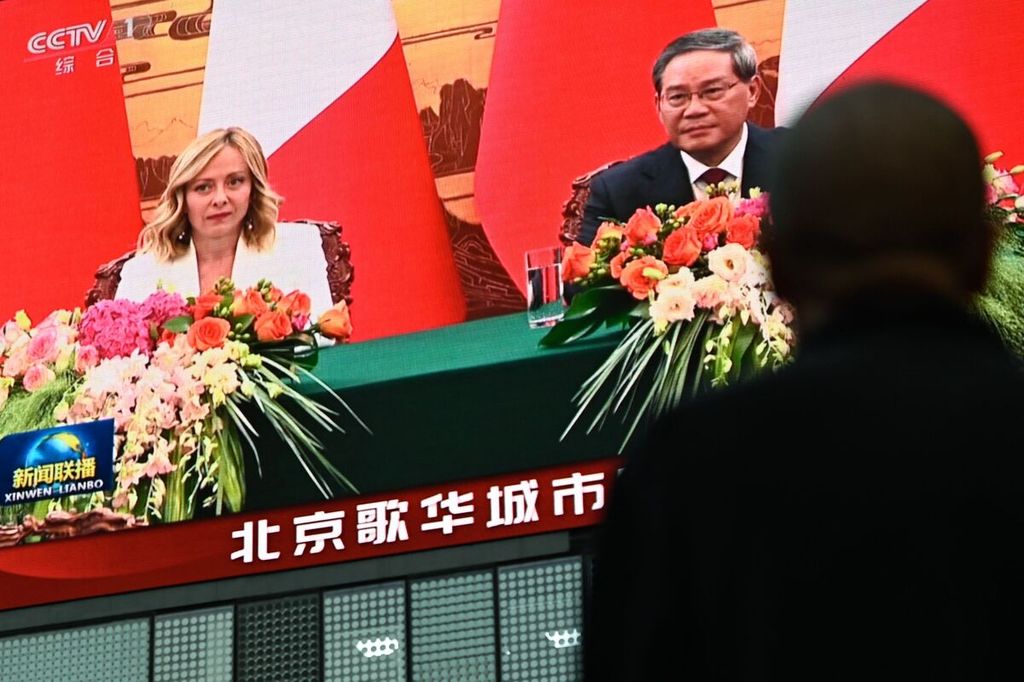 Warga Beijing, China, di depan layar raksasa yang menampilkan Perdana Menteri Li Qiang (kanan) dengan PM Italia Giorgia Meloni, Minggu (28/7/2024).