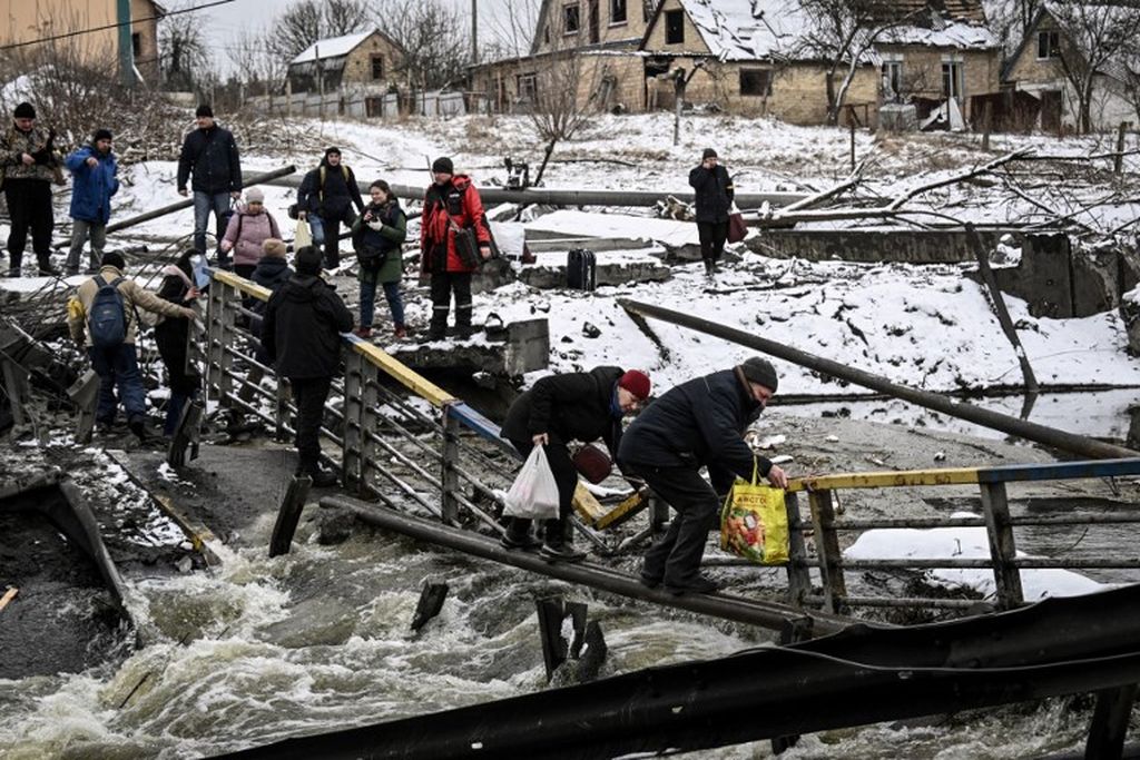 Warga sipil menyeberangi sungai di jembatan yang diledakkan di sisi utara Kiev, pada 1 Maret 2022.  "Mempertahankan ibu kota Kiev," kata Presiden Volodymyr Zelenskyy sebagai "prioritas utama" Ukraina.