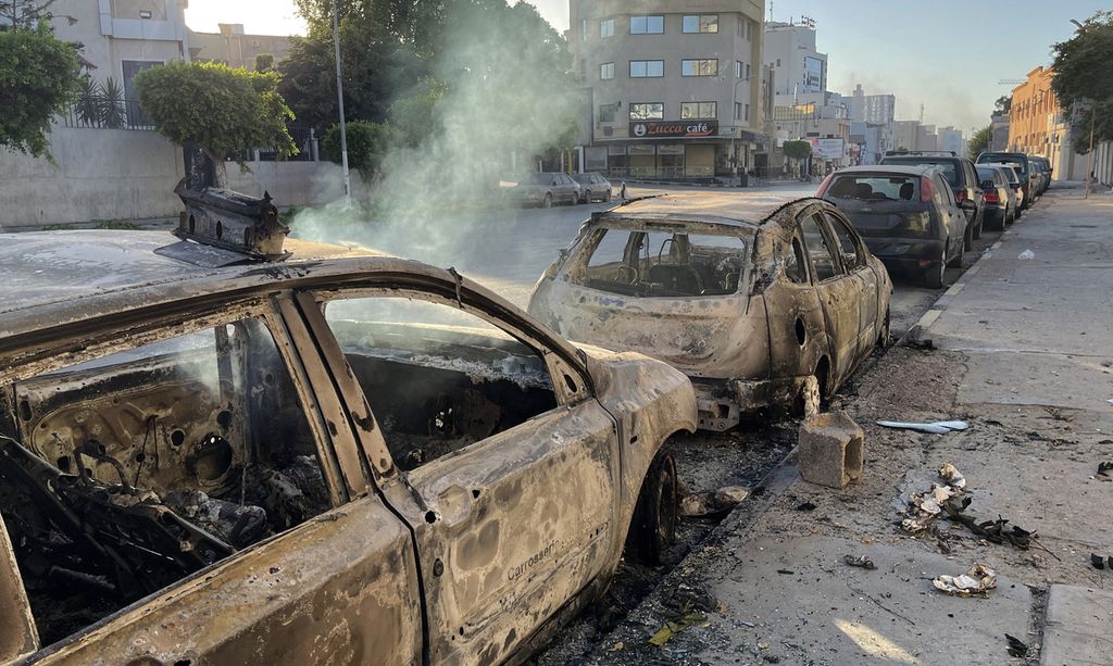 Mobil-mobil terbakar di sebuah ruas jalan di ibu kota Libya, Tripoli, 27 Agustus 2022, setelah kerusuhan di antara kelompok yang bertikai. Setidaknya 32 orang tewas dalam kerusuhan tersebut. 