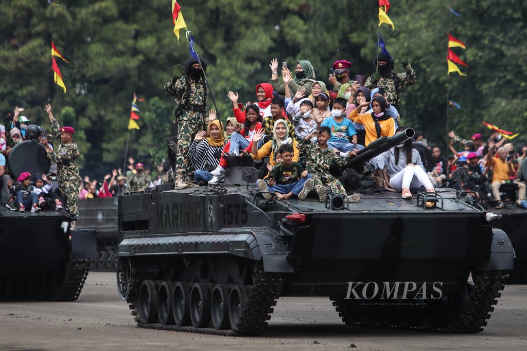 Warga menaiki tank milik Korps Marinir TNI Angkatan Laut saat upacara peringatan HUT Ke-77 Korps Marinir di Lapangan Kesatrian Marinir Hartono, Cilandak, Jakarta Selatan, Selasa (15/11/2022).