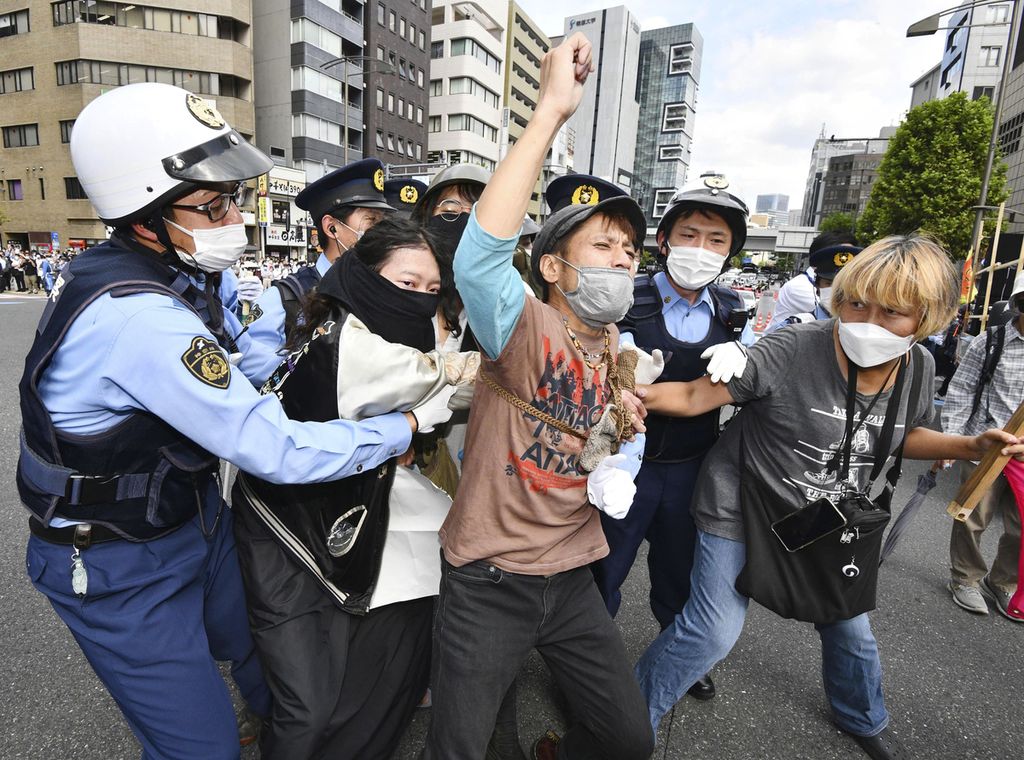 Aparat kepolisian menghalau para pengunjuk rasa yang menentang pemakaman kenegaraan bagi mantan Perdana Menteri Jepang Shinzo Abe di Tokyo, Jepang, Selasa (27/9/2022). 