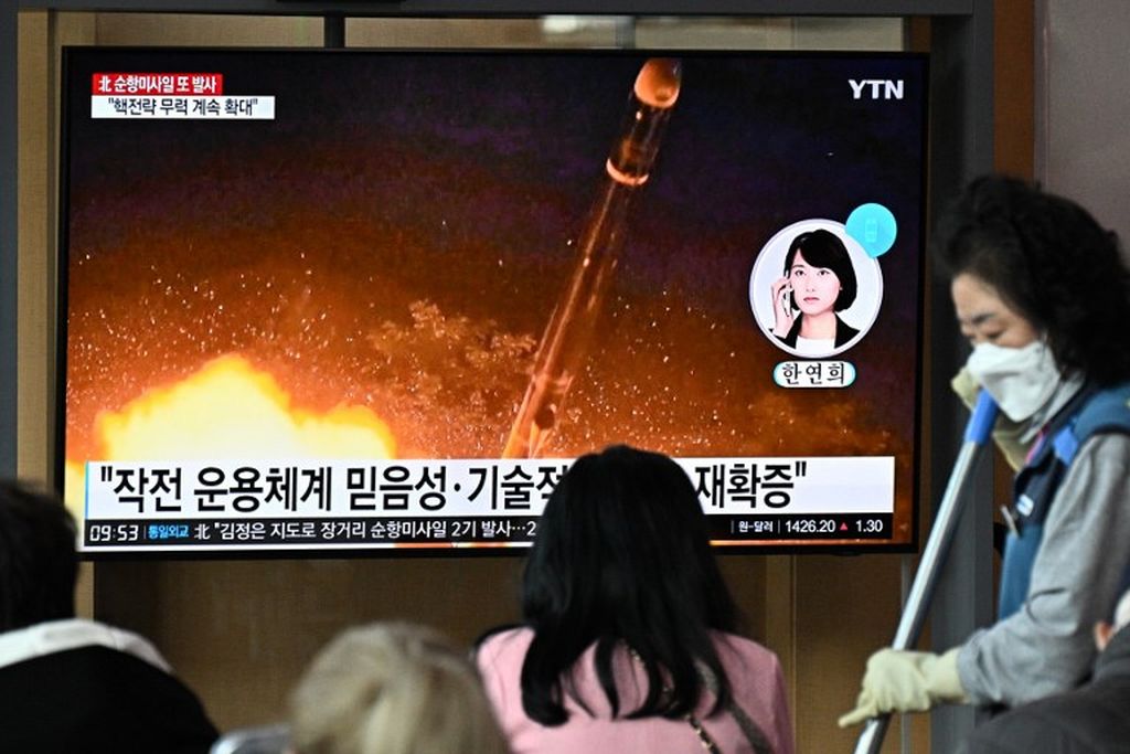 Seorang pegawai stasiun televisi membersihkan lantai di dekat monitor televisi yang menyiarkan berita dokumentasi video uji coba rudal Korea Utara di sebuah stasiun kereta api di Seoul, 13 Oktober 2022. Pemimpin Korut Kim Jong Un saat itu mengawasi peluncuran dua rudal jelajah jarak jauh. 