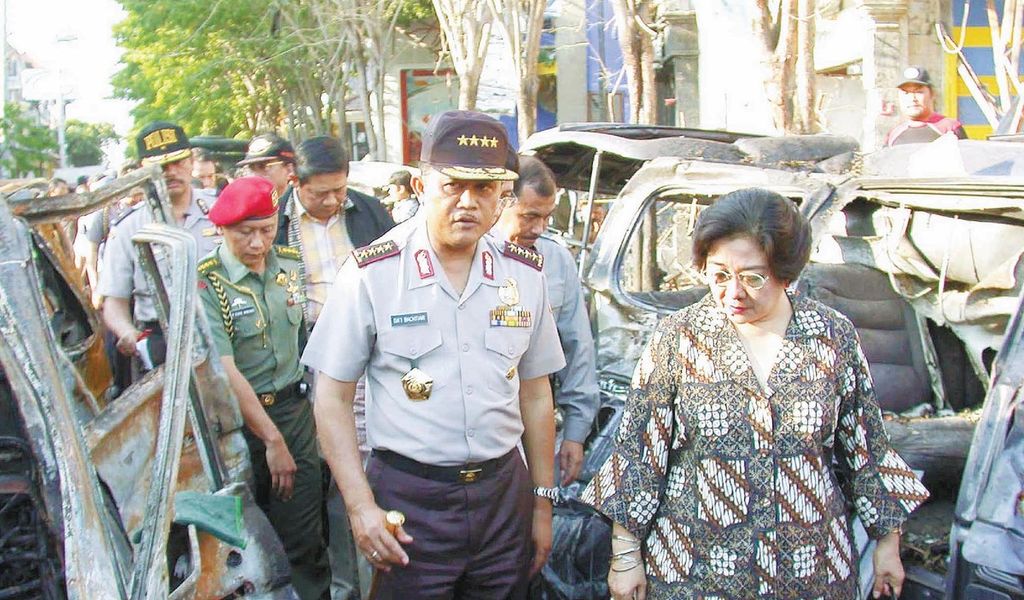Presiden Megawati Soekarnoputri, Minggu (13/10/2002), berjalan melintasi mobil-mobil yang hancur akibat ledakan bom saat mengunjungi lokasi peledakan bom hari Sabtu malam di Kuta dan Renon, Bali. 