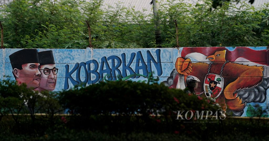 Pengendara melintasi mural pahlawan nasional Soekarno-Hatta di Jalan Pemuda, Jakarta Timur, Selasa (5/10/2021). 