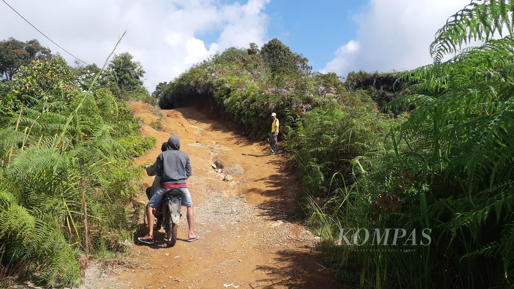 Dua warga berusaha mengendarai motor menuju Dusun IV, Desa Cahaya Alam, Kecamatan Semende Darat Ulu, Kabupaten Muara Enim, Sumatera Selatan, Selasa (19/7/2022). Dusun IV hampir terisolasi karena belum teraliri listrik dan akses jalan menuju dusun terbatas.