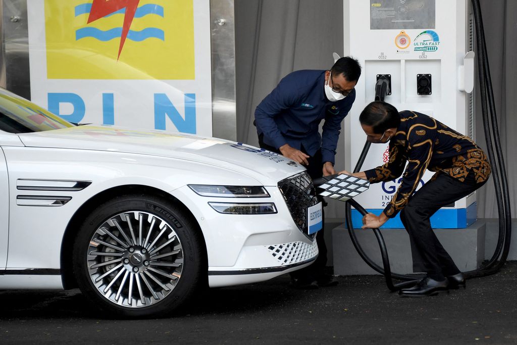 Presiden Indonesia  Joko Widodo memperlihatkan cara mengsi daya  pada kendaraan listrik (25/3/2022). Kendaraan listrik digunakan sebagai moda transportasi bagi para delegasi G20 di Nusa Dua, Bali. 