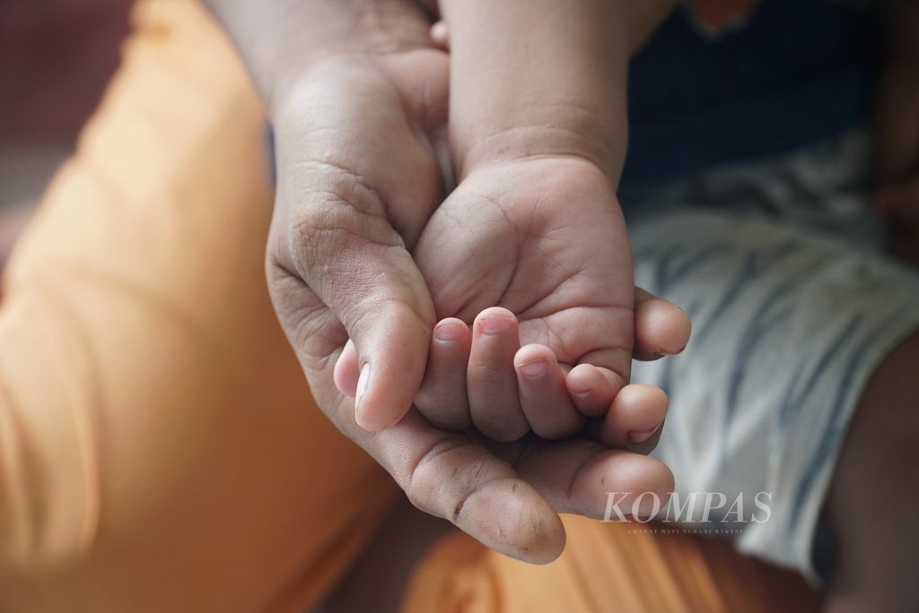 Seorang ibu menggenggam tangan anaknya yang mengalami tengkes atau <i>stunting</i> di Dusun Koritbuah, Desa Sinaka, Kecamatan Pagai Selatan, Kepulauan Mentawai, Sumatera Barat, Minggu (18/6/2023). Pada 23 Mei 2023, ada 29 kasus <i>stunting</i> di Desa Sinaka.