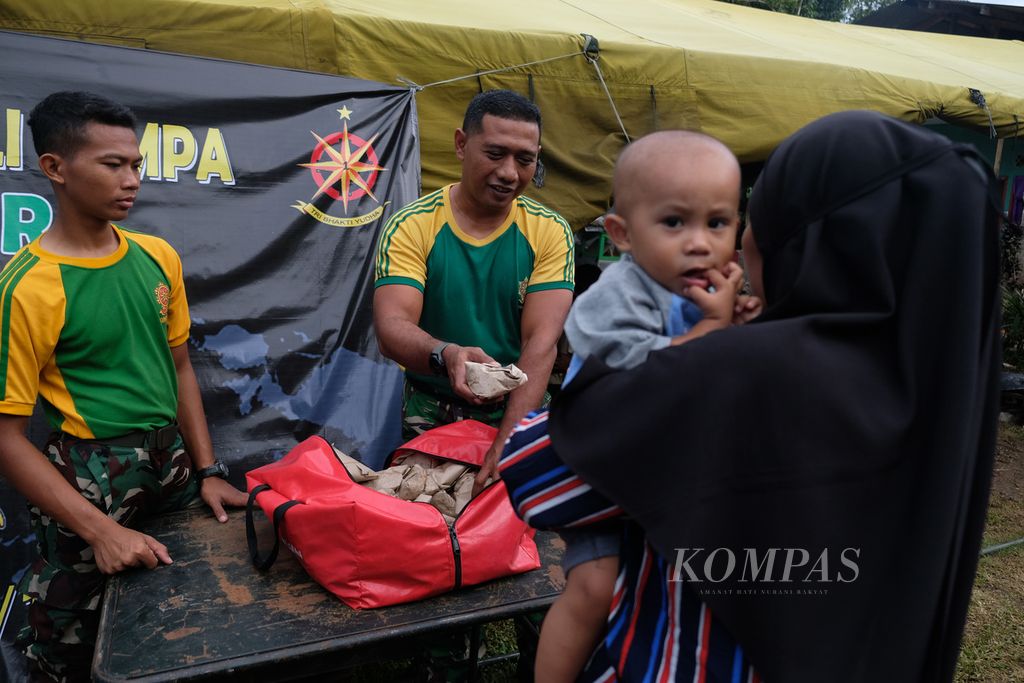 Salah satu prajurit dari Yon Bekang 1 Kostrad Cibinong memberikan makanan kepada warga di dapur umum Kostrad TNI AD di Kampung Cileungsi, Desa Sukajaya, Kecamatan Cugenang, Kabupaten Cianjur, Selasa (29/11/2022).