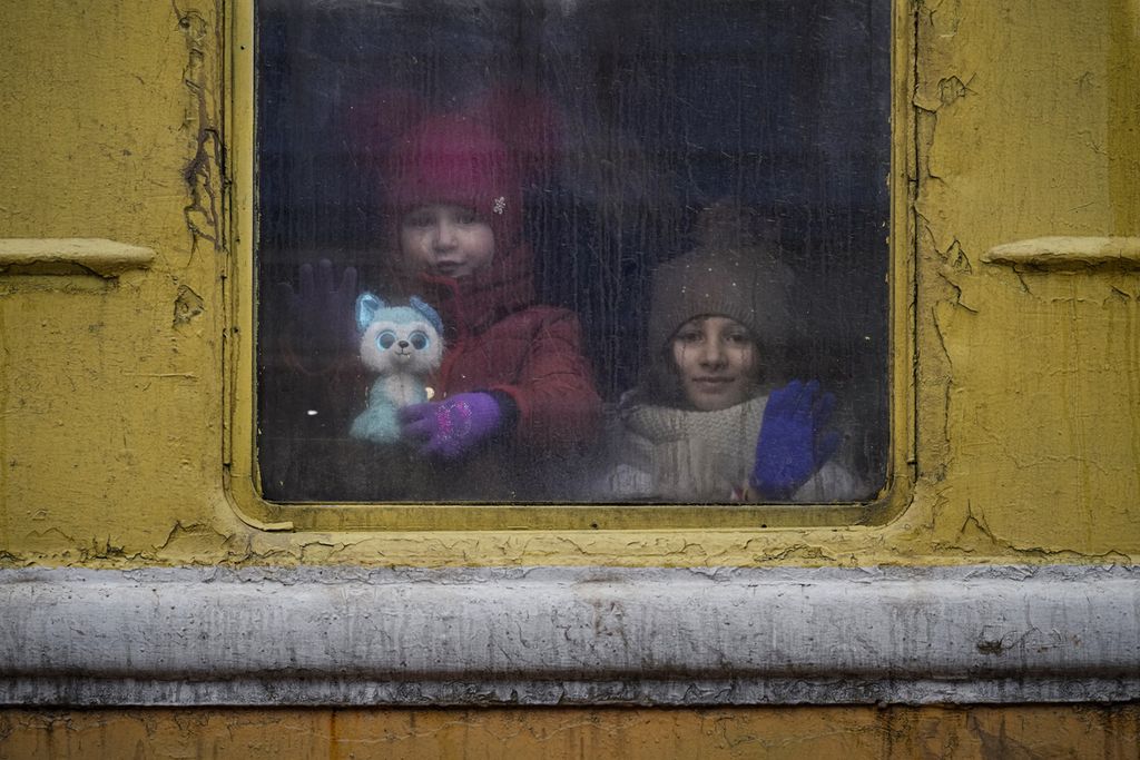 Dua anak melihat ke luar jendela kereta api yang akan membawa mereka mengungsi ke Lviv dari Kiev, Kamis (3/3). (AP Photo/Vadim Ghirda)