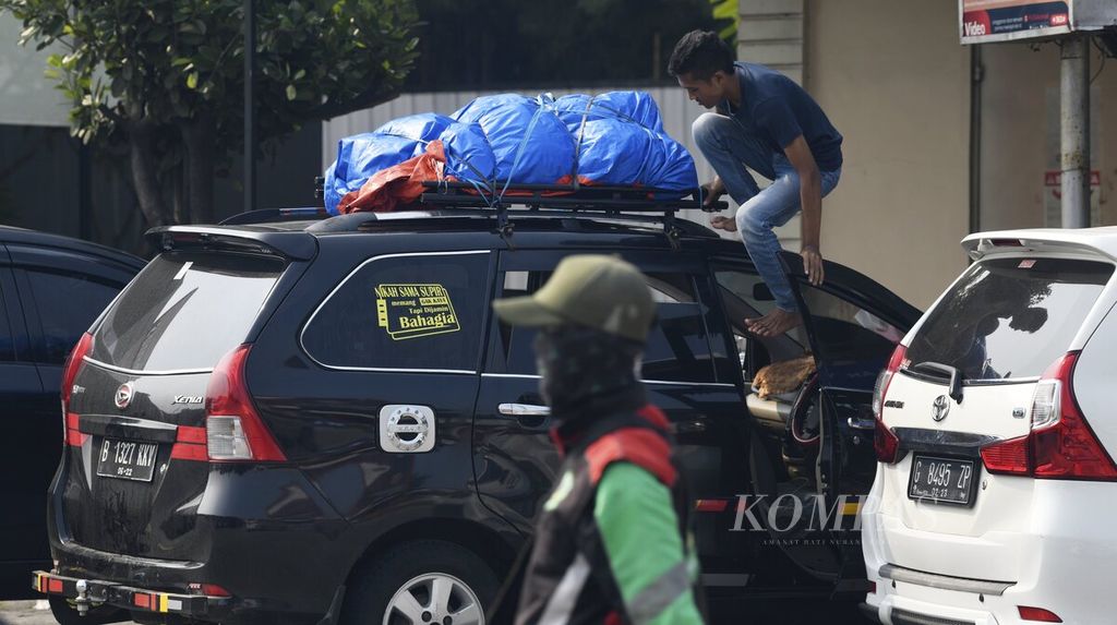Salah seorang pemudik memeriksa barang bawaan yang diletakkan pada atap kendaraan saat beristirahat di Kilometer 57 Jalan Tol Jakarta-Cikampek, Senin (25/4/2022). 
