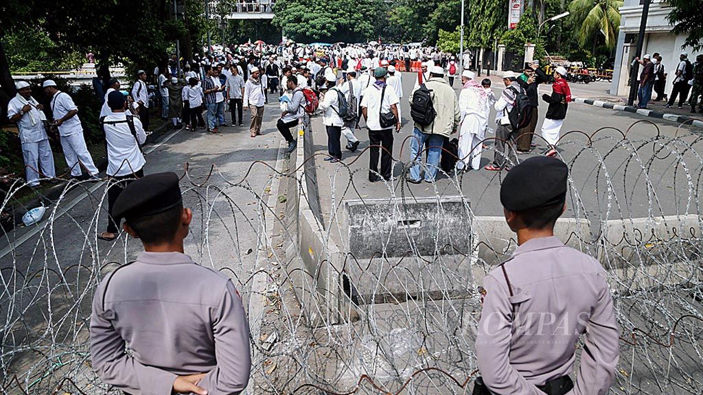 Polisi  berjaga di sekitar blokade kawat berduri yang terpasang di Jalan Ir H Juanda, Jakarta Pusat, Jumat (5/5). Sejumlah barikade dipasang di seputaran kawasan Istana Kepresidenan saat massa dari sejumlah elemen melakukan unjuk rasa.