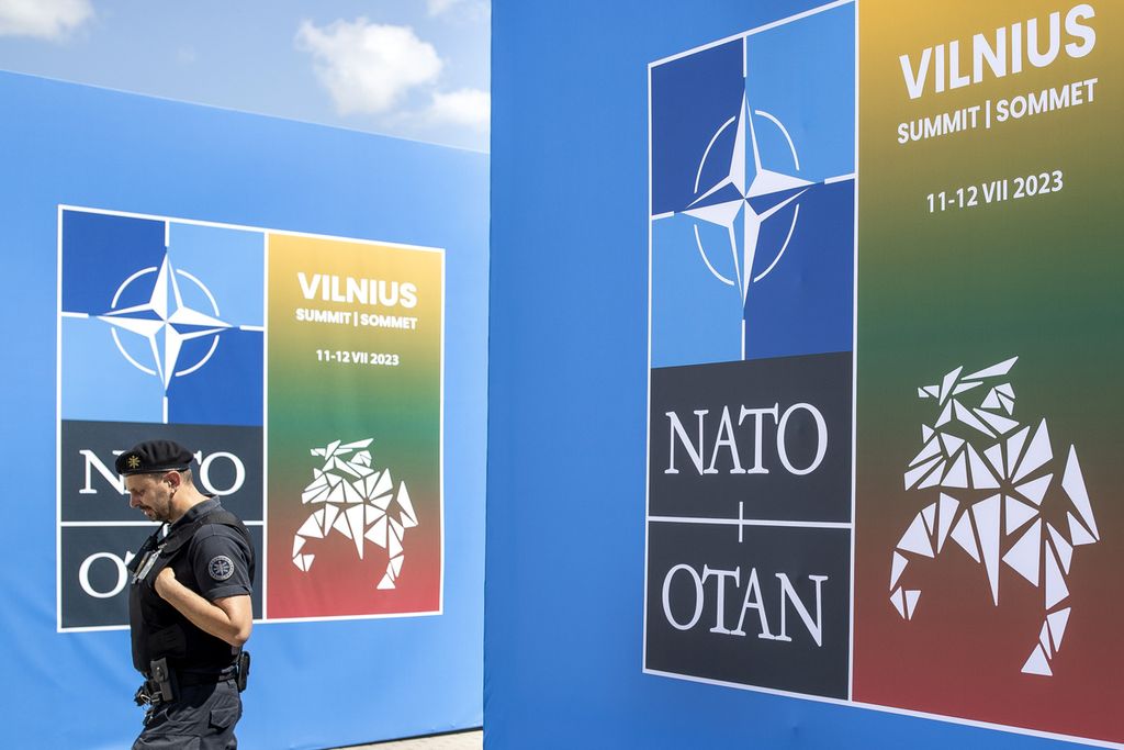 Seorang petugas keamanan berjaga di depan banner yang terletak tidak jauh dari lokasi penyelenggaraan KTT NATO di Ibu Kota Lithuania, Vilnius, Minggu (9/7/2023). Dua hal yang diduga akan menjadi diskusi hangat selama KTT, yaitu aksesi keanggotaan Swedia dan pengiriman bom tandan untuk Ukraina.. 