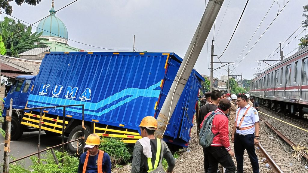 Kereta dari arah Rangkasbitung melintas di lajur hulu berjalan lambat karena proses evakuasi truk barang yang menabrak tiang listrik aliran atas (LAA) di jalur rel listrik di Km 17+5 antara Stasiun Pondok Ranji-Kebayoran, Jalan Bintaro Permai IV, Pesanggrahan, Jakarta Selatan, Selasa (25/7/2023).