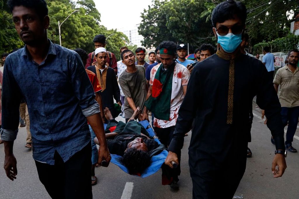 Para pengunjuk rasa membawa mahasiswa yang terluka dalam demonstrasi di Dhaka, Bangladesh, Minggu (4/8/2024).