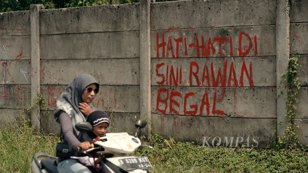 Warga melintasi mural waspada tindak kejahatan di Bantargebang, Kota Bekasi, Jawa Barat, Jumat (2/9/2022). Langkah pencegahan terhadap beragam kejahatan jalanan di Ibu Kota dan sekitarnya krusial dilakukan. Masyarakat membutuhkan rasa aman.