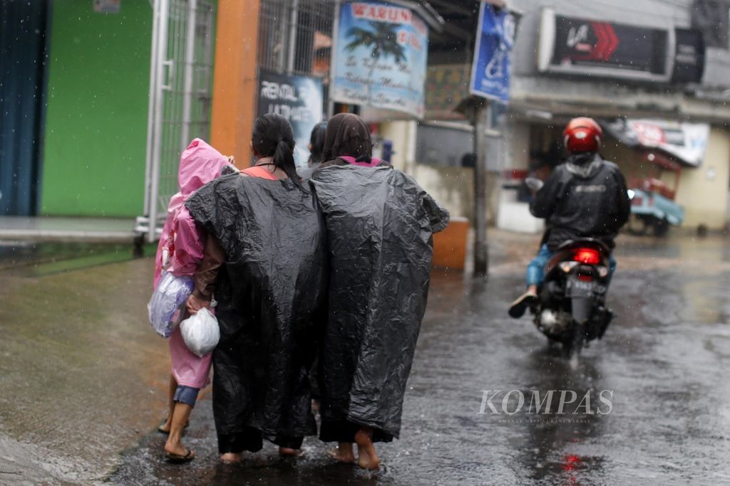 Anak-anak mengenakan jas hujan untuk menghindari hujan saat pulang sekolah di kawasan Pondok Aren, Tangerang Selatan, Banten, Rabu (7/9/2022). BMKG memprediksi awal musim hujan di Indonesia akan terjadi pada September hingga November 2022 dengan puncak musim hujan terjadi pada Desember 2022 dan Januari 2023.