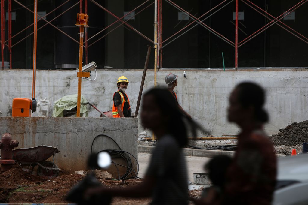 Workers on the construction project for business premises and apartments leave their work area during their lunch break in Serpong, South Tangerang, Sunday (13/2/2022). Regulation of the Minister of Manpower (Permenaker) of the Republic of Indonesia Number 2 of 2022 raises pros and cons among workers.