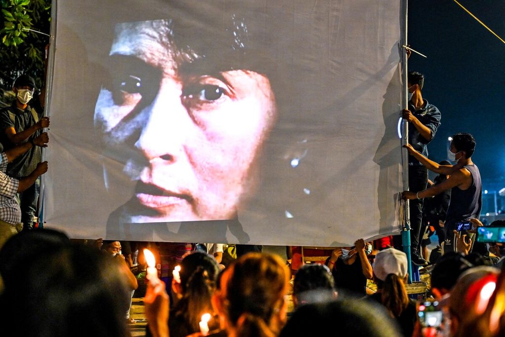 Gambar wajah tokoh politik Aung San Suu Kyi ditampilkan di layar melalui proyektor dalam unjuk rasa malam di Yangon, Myanmar, dalam foto yang diambil pada 13 Maret 2021. Suu Kyi ditahan oleh militer seusai kudeta 1 Februari 2021.  