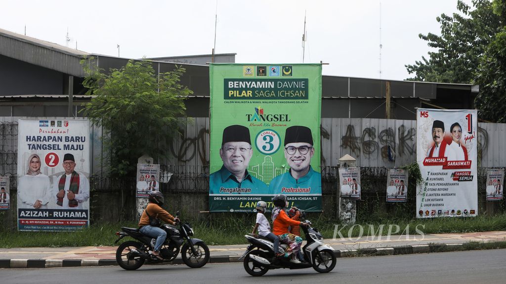 Pengendara sepeda motor melintas di depan baliho kampanye tiga pasangan calon wali kota-wakil wali kota Tangerang Selatan di Jalan Tekno Widya, Tangerang Selatan, Jumat (13/11/2020). 