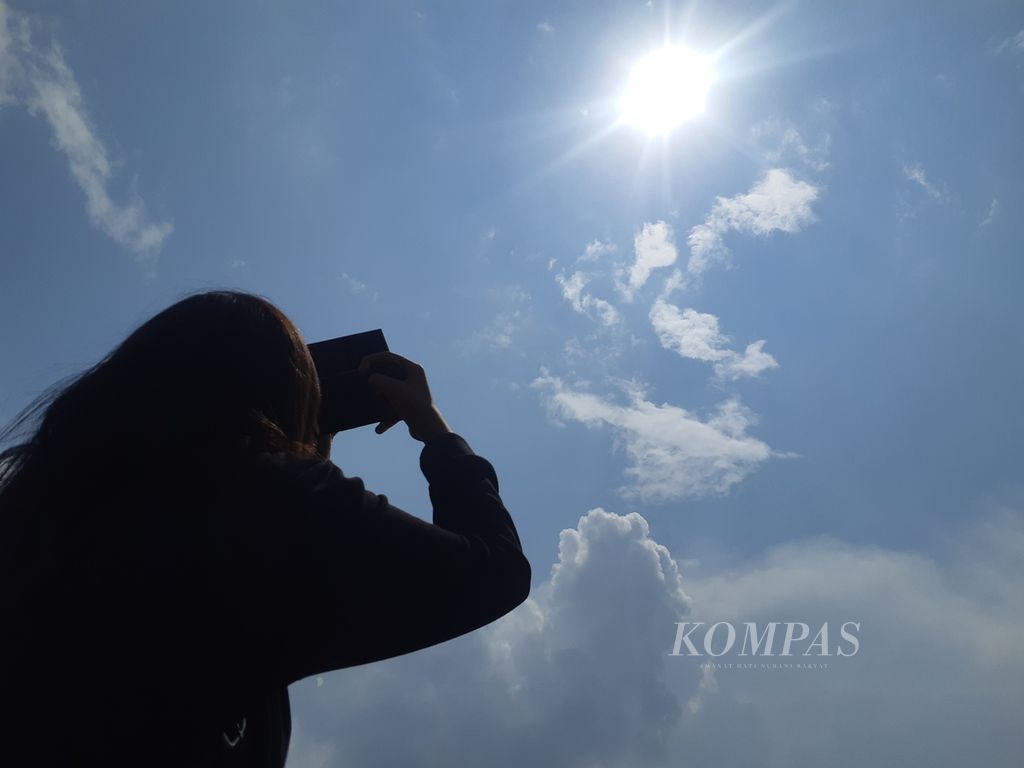 Seorang warga sedang melihat fenomena gerhana matahari di kawasan Benteng Kuto Besak, Palembang, Kamis (20/4/2023). Antusiasme masyarakat Palembang melihat gerhana matahari terbilang rendah karena kurangnya sosialisasi.